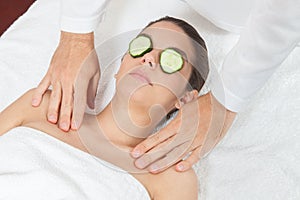 Woman with cucumber on her face gets a massage