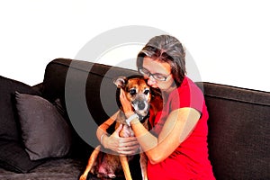 Woman cuddling with dog on a grey sofa