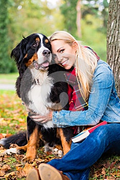 Woman cuddling with dog outside in park