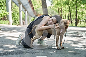 Woman cuddling her funny brown dog while sitting at the road