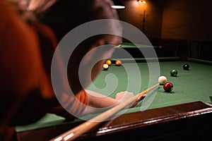 Woman with cue pointing at billiard ball at table. Playing billiards concept