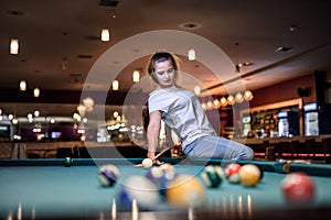 Woman with cue sitting on billiard table and posing