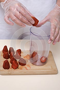 woman in culinary gloves prepares strawberry dessert