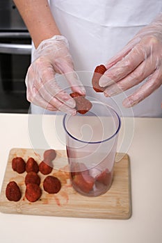 woman in culinary gloves prepares strawberry dessert