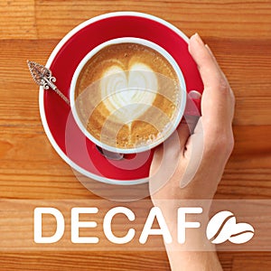 Woman with cup of aromatic decaf coffee at wooden table, top view