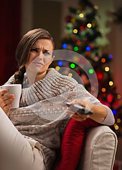 Woman with cup of beverage get bored looking TV