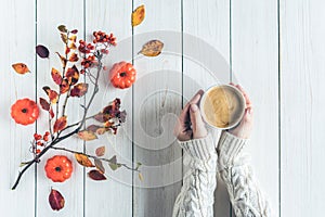 Woman with cup of coffee, leaves, small pumpkins and rowan on white retro wood boards. background. Autumn, fall concept. Flat lay,