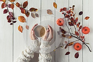 Woman with cup of coffee, leaves, small pumpkins and rowan on white retro wood boards. background. Autumn, fall concept. Flat lay,