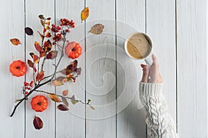 Woman with cup of coffee, leaves, small pumpkins and rowan on white retro wood boards. background. Autumn, fall concept. Flat lay,