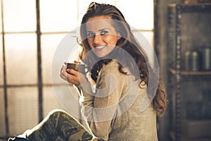 Woman with cup of coffee in loft apartment