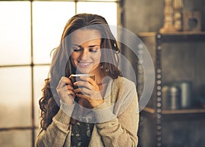 Woman with cup of coffee in loft apartment