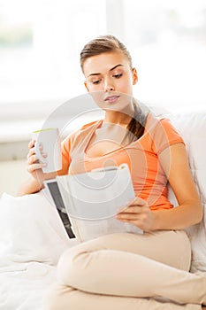 Woman with cup of coffee reading magazine at home