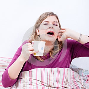 Woman with cup of coffee yawning