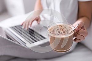 Woman with cup of morning coffee working on laptop, closeup