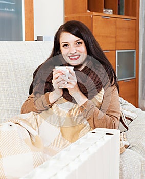 Woman with cup near electric heater