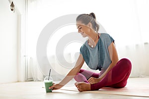 Woman with cup of smoothie at yoga studio