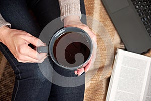 Woman with a Cup of tea, a book, a laptop on a blanket