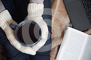 Woman with a Cup of tea, a book, a laptop on a blanket