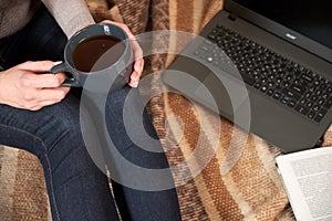 Woman with a Cup of tea, a book, a laptop on a blanket