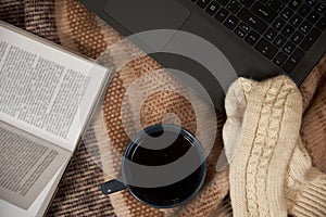 Woman with a Cup of tea, a book, a laptop on a blanket