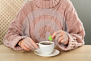 Woman with cup of tea at wooden table, closeup