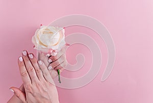 Woman cupped hands with pink manicure holding a flowers