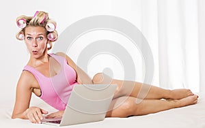 Woman with curlers in bed with laptop