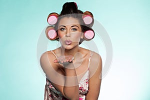 woman in curlers blowing a kiss
