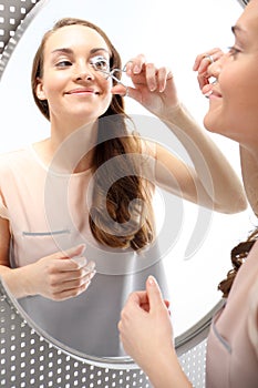 Woman curls lashes eyelash curler .