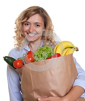 Woman with curly blond hair and a bag full of healthy food