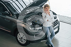 Woman with curly blonde hair is in autosalon