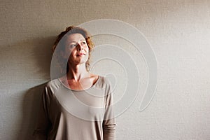 Woman with curly hair leaning on wall in contemplation