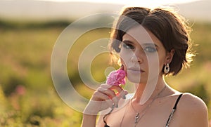 woman with curly hair posing near roses in a garden. The concept of perfume advertising