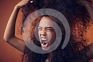 Woman, curly hair and scream with anger in studio on brown background for damage, treatment and bad result. Female