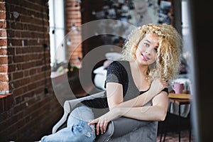 Woman with curly hair sitting in an armchair