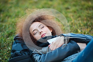 Woman with curly hair sleeping on green grass