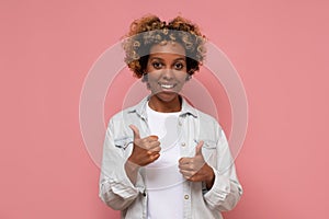 Woman with curly hair wearing casual clothes doing happy thumbs up gesture with hand