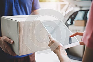 Woman customer appending signature in digital tablet and receiving a cardboard boxes parcel from delivery service courier, Home d