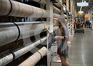 Woman customer choosing linoleum flooring in hypermarket photo