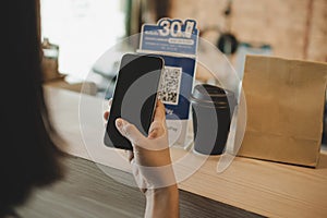 Woman customer using digital mobile phone scan QR code pay for buying coffee in modern cafe coffee shop