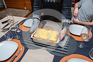 Woman cut with knife hot tasty home baking lasagna in ceramic casserole dish