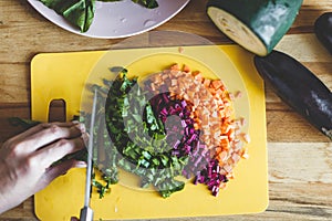 Woman cut vegetables on the yellow cutting board