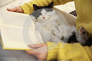 Woman with cute cat reading book, closeup