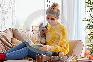 Woman with cute dog reading book at home