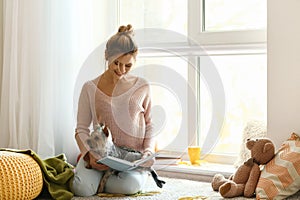 Woman with cute dog reading book at home