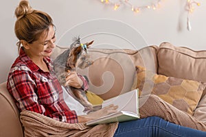 Woman with cute dog reading book at home