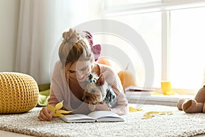 Woman with cute dog reading book at home on autumn day