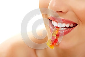 Woman with cute sweet candy closeup in teeth