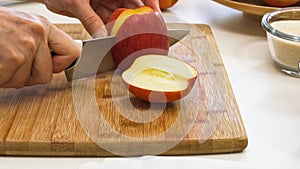 Woman cuts apples on a wooden cutting board.