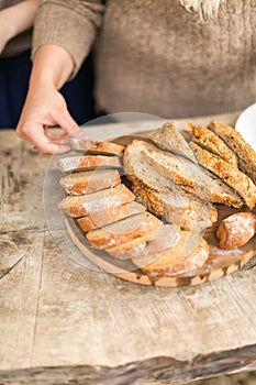 The woman cuts bread on a wooden board.